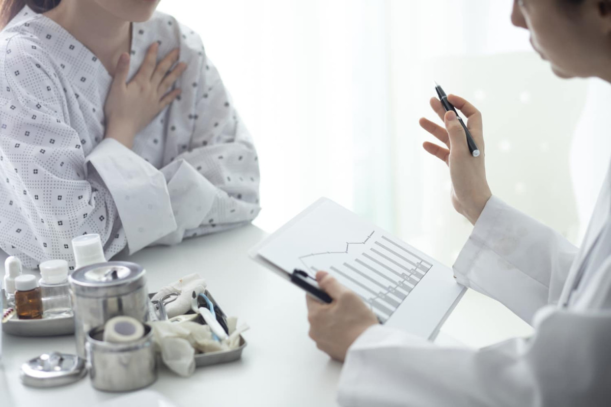 A doctor shows a patient a chart during a consultation at a medical office, with various medical supplies on the table.