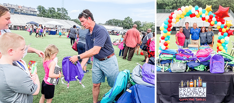 People distribute backpacks to children at an outdoor event; a table with backpacks and a "Project Backpack" sign is decorated with balloons.