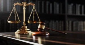 Close-up of empty justice scales and gavel placed on the corner of a shiny judge's bench.