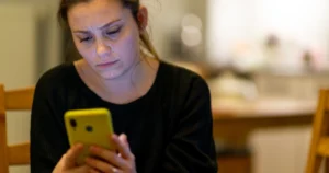 An upset woman holding her phone.