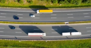 Cars on the road alongside semi trucks.