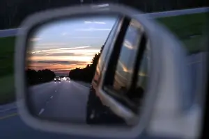 car in side view mirror at dusk