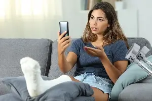 young woman with cast on her leg using social media