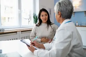 female patient holding stomach, talking to doctor